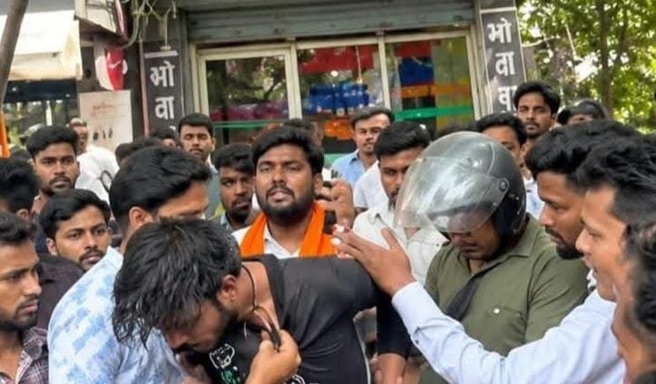 डिमना चौक स्थित मोबाइल दुकान में हंगामे के बाद जुटी भीड़ और पुलिस कर्मी